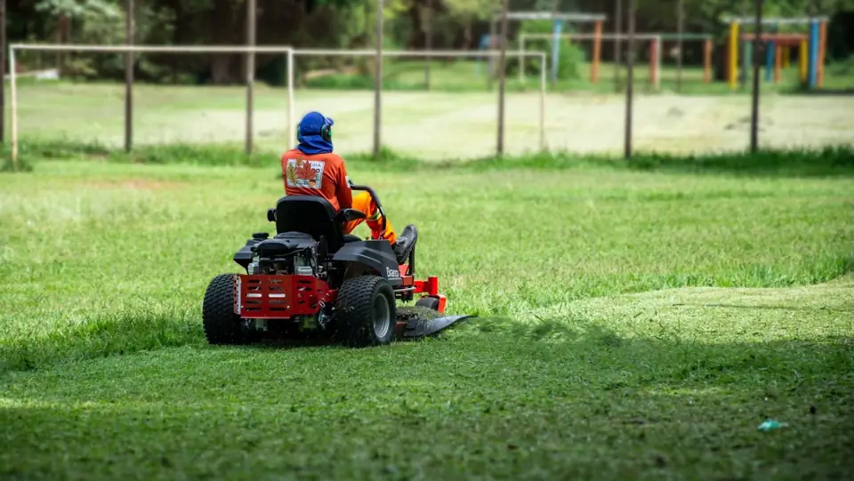 MAFAM crew member mowing a large lawn on a riding mower
