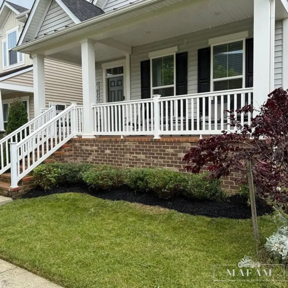 Front porch with fresh mulch beds, trimmed shrubs and a cut lawn